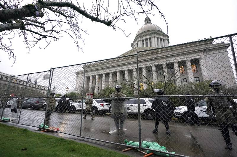 Members of the Washington National Guard stand near a fence surrounding the Capitol in anticipation of protests Monday, Jan. 11, 2021, in Olympia, Wash.