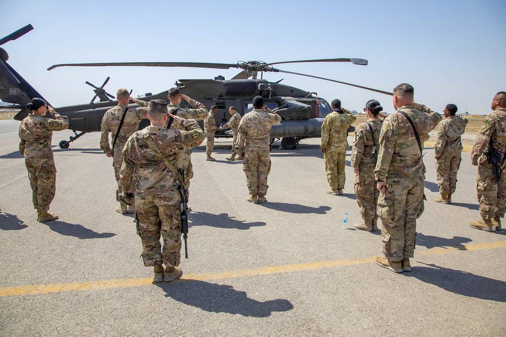 U.S. soldiers salute as the United States flag is folded at the conclusion of a reenlistment ceremony at Erbil Air Base in the Kurdistan Region of Iraq, May 22, 2020.