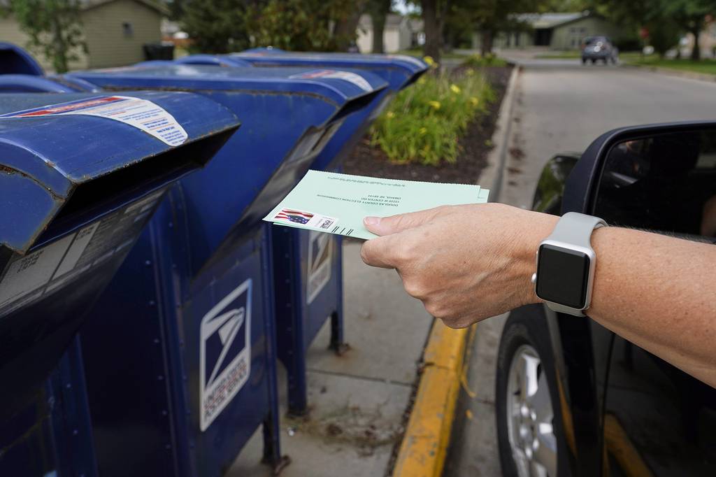 In this Aug. 18, 2020, file photo, a person drops applications for mail-in-ballots into a mailbox in Omaha, Neb.