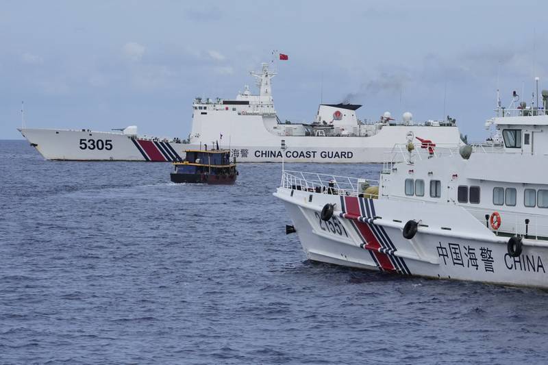 A Philippine supply boat, center, maneuvers around Chinese coast guard ships as they tried to block its way near Second Thomas Shoal, locally known as Ayungin Shoal, at the disputed South China Sea on Tuesday, Aug. 22, 2023.