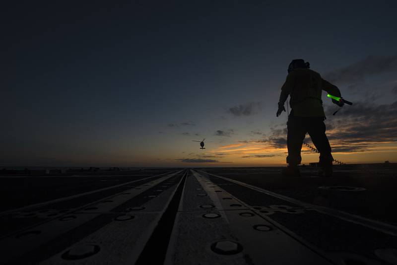 Navy Boatswain's Mate Seaman Cristian Martinez directs an MH-60S Sea Hawk helicopter on the flight deck aboard the guided-missile cruiser USS Vella Gulf (CG 72) in the Atlantic Ocean, July 10, 2019.