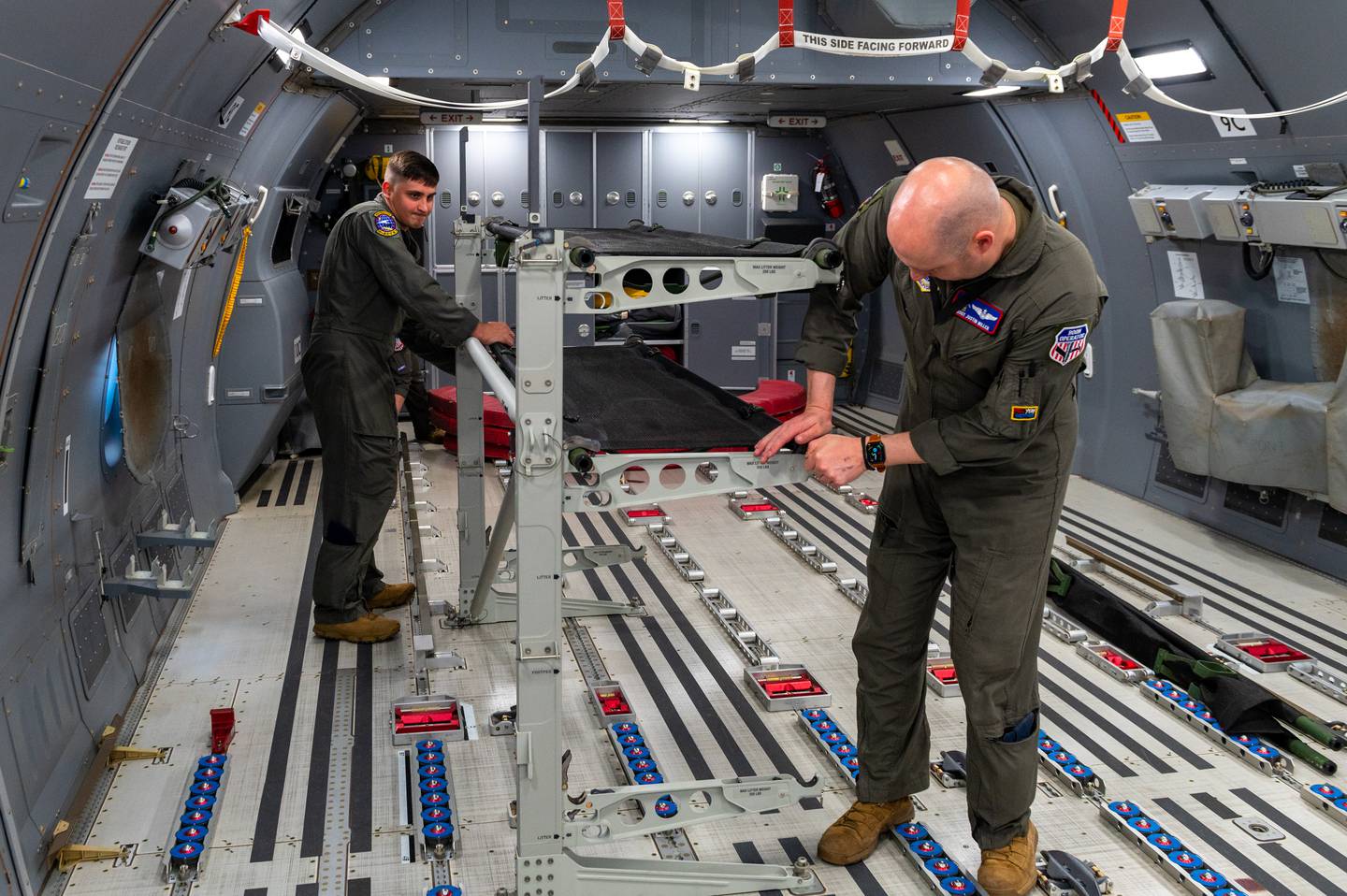 Staff Sgt. Jonathan Sanders and Master Sgt. Justin Miller, 349th Air Refueling Squadron boom operators, set up palletized cots in the back of a KC-46A Pegasus May 5, 2022.  (Airman Brenden Beezley/Air Force)