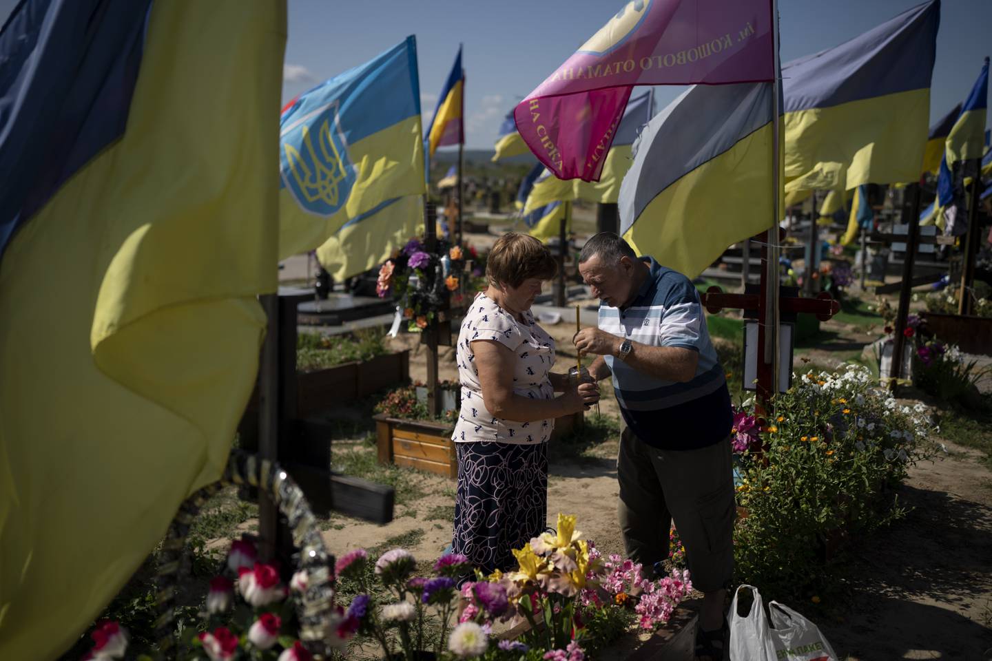 Kateryna and Oleh light a candle at a cemetery in front of their son's grave, who died fighting in the war as Ukrainians mark Independence Day in Kharkiv, Ukraine, Thursday, Aug. 24, 2023.