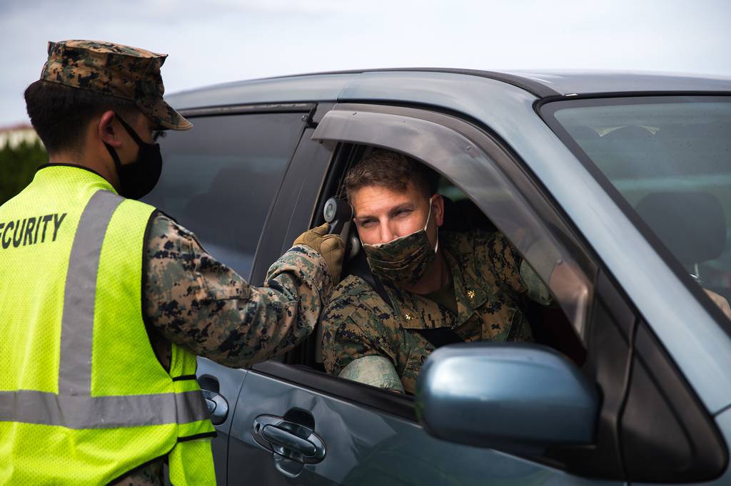 U.S. Marine Corps Lance Cpl. Aaron Santos conducts temperature checks on outbound traffic at Camp Courtney, Okinawa, Japan, July 13, 2020.