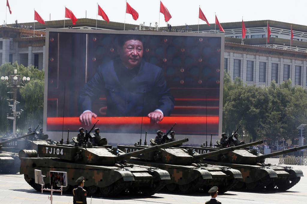 In this Sept. 3, 2015, file photo, Chinese President Xi Jinping is displayed on a screen as Type 99A2 Chinese battle tanks take part in a parade commemorating the 70th anniversary of Japan's surrender during World War II held in front of Tiananmen Gate in Beijing.