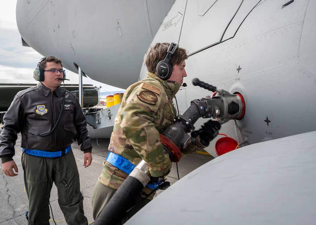 Tech Sgt. Connor Oswald, loadmaster assigned to the 4th Airlift Squadron, connects a fuel hose during a wet-wing defuel while Senior Airman John Soto, loadmaster assigned to the 4th Airlift Squadron, overlooks, June 16, 2021 at Thule Air Base, Greenland. (Airman Mira Roman/Air National Guard)