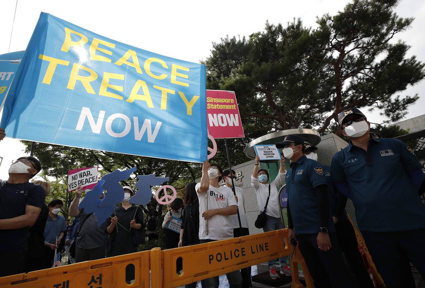 Protesters wearing face masks hold banners as police officers stand guard during a rally to demand the peace on the Korean Peninsula and to stop sanctions against North Korea in front of Foreign Ministry before U.S. Deputy Secretary of State Stephen Biegun's arrival to meet with South Korean officials in Seoul, South Korea, on July 8, 2020.