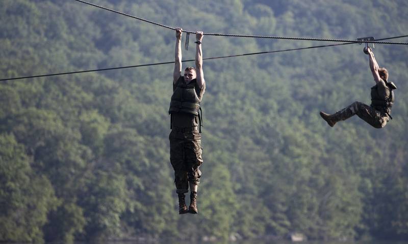 Cadets hang above a lake as they navigate a water obstacle course, Friday, Aug. 7, 2020, in West Point, N.Y.