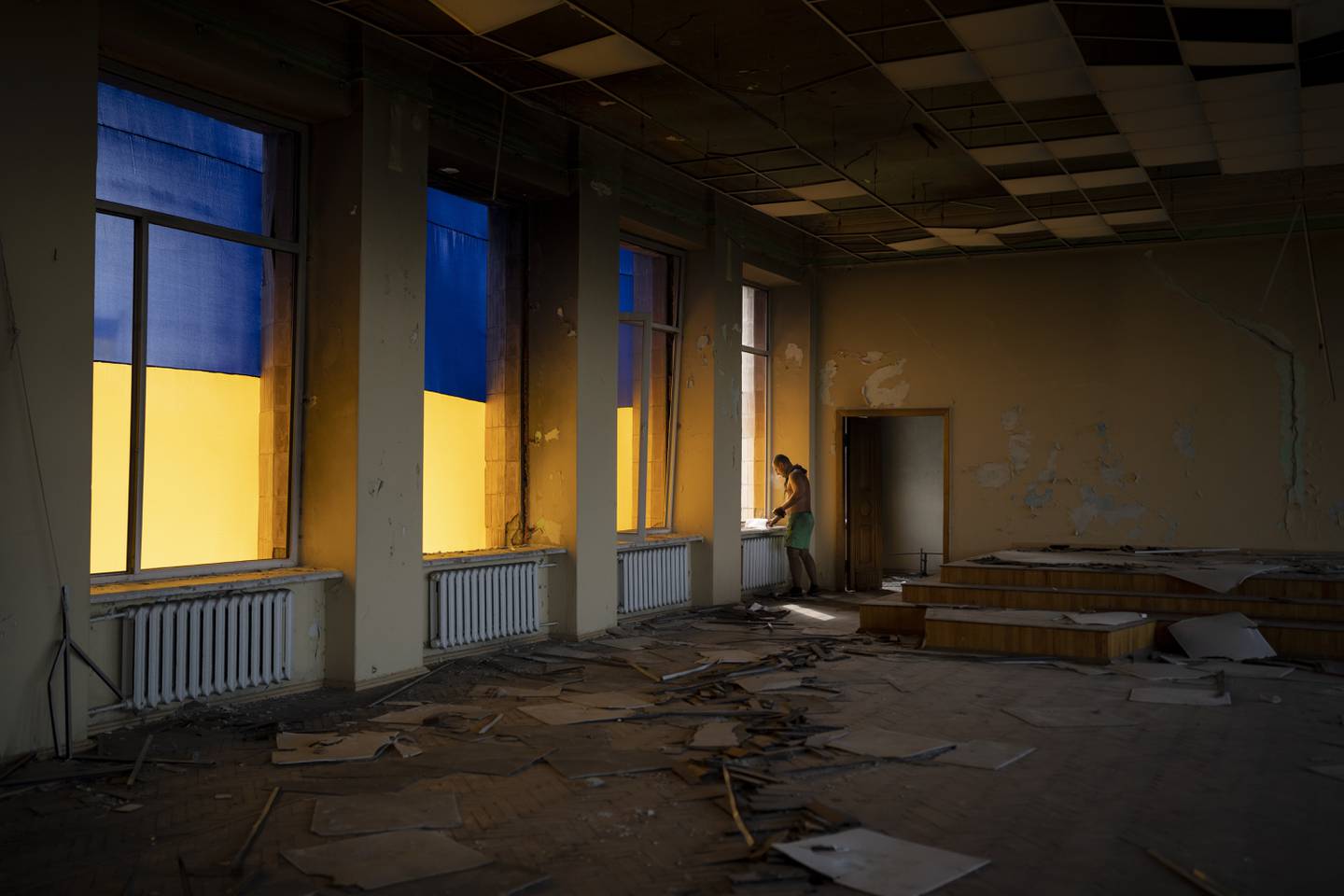 A construction worker looks out of a window of the damaged city council building in Izyum, Ukraine, Tuesday, Aug. 22, 2023.