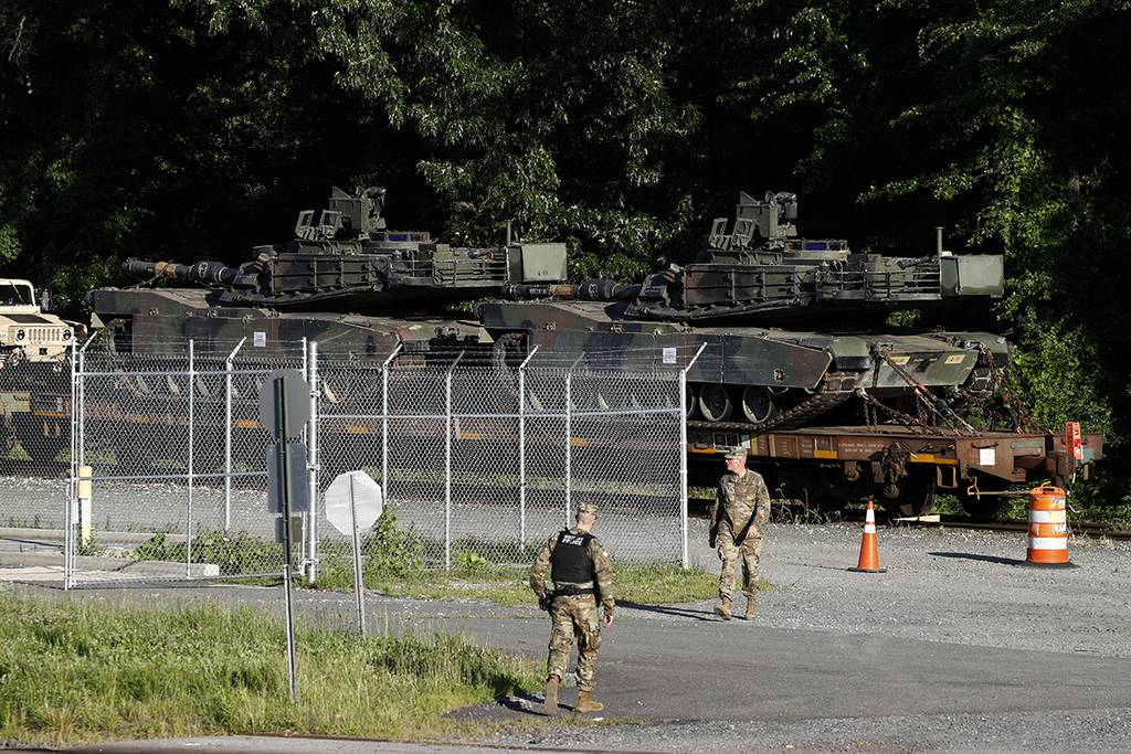 Military police walk near Abrams tanks on a flat car in a rail yard, Monday, July 1, 2019, in Washington, ahead of a Fourth of July celebration that President Donald Trump says will include military hardware.