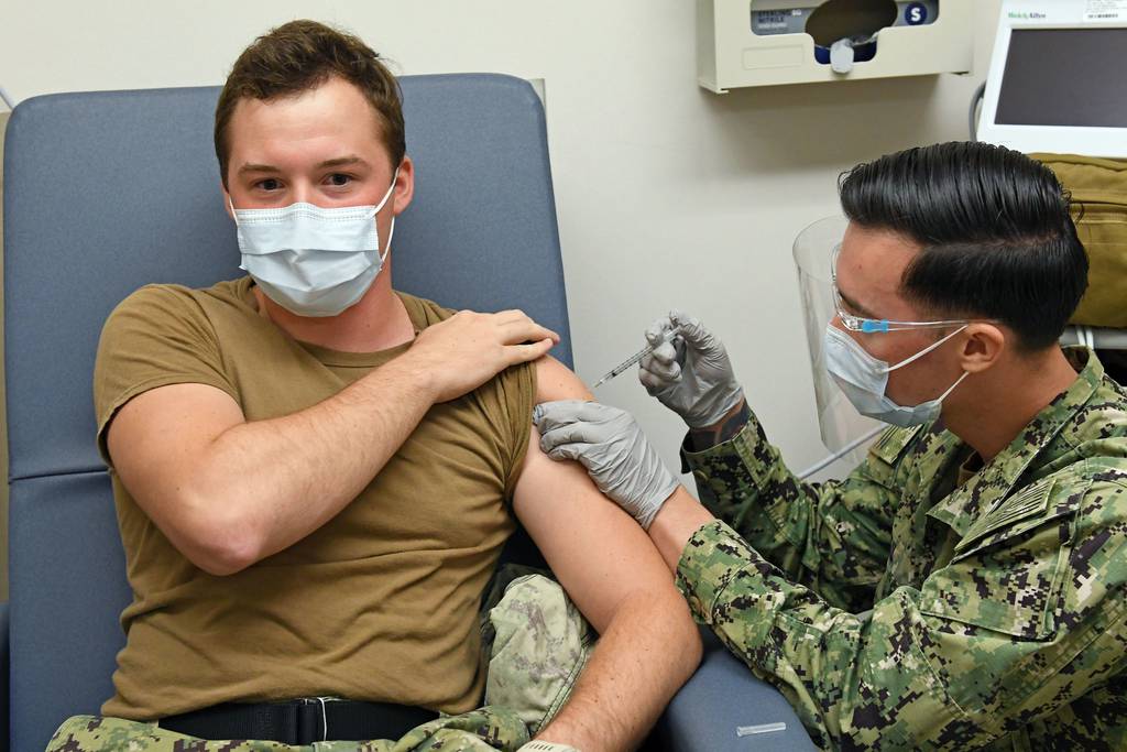 Hospital Corpsman 3rd Class David Tuil, assigned to the Preventive Medicine Department at Naval Health Clinic Hawaii, administers a Pfizer-BioNTech COVID-19 vaccine to Hospital Corpsman 3rd Class Gage Finn, Dec. 16, 2020.