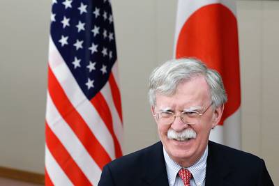 U.S. National Security Adviser John Bolton walks past U.S. and Japanese flags prior to a meeting with Japanese Foreign Minister Taro Kono in Tokyo Monday, July 22, 2019.