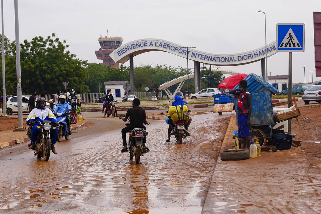 Motorcyclists ride by the entrance of the airport in Niamey, Niger, Tuesday, Aug. 8, 2023.