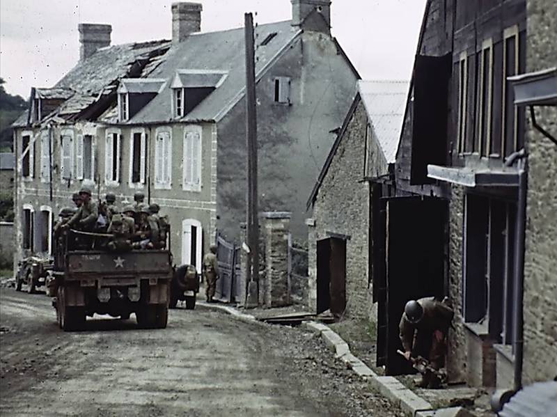 U.S. troops drive through a town during World War II in France