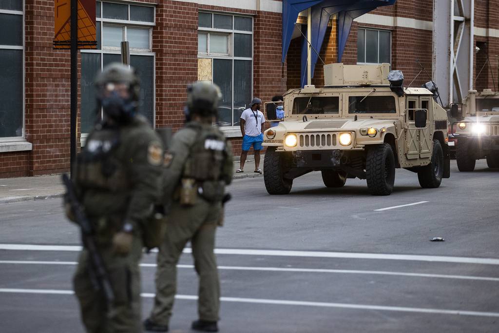 National Guard vehicles drive into downtown behind police officers in riot gear as protests occur on May 30, 2020, in Louisville, Ky.