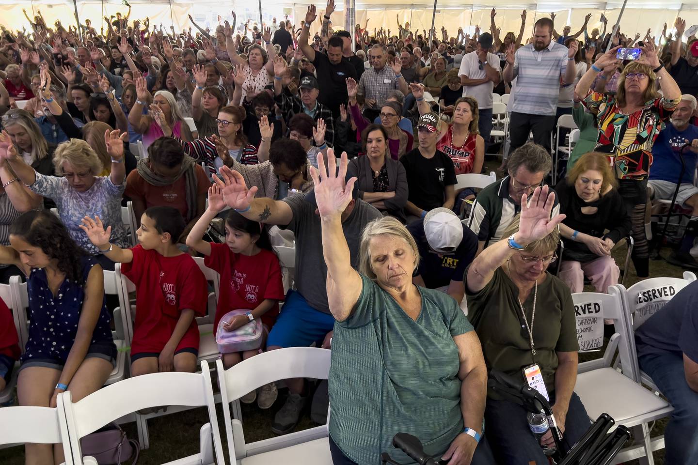 Attendees raise their hands as they worship inside the tent during the ReAwaken America tour at Cornerstone Church, in Batavia, N.Y., Friday, Aug. 12, 2022.