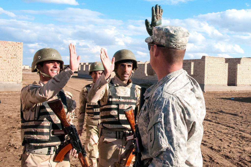 A U.S. Army infantry trainer offers "high fives" to two Iraqi Army trainees at the conclusion of the day's infantry squad tactical training lanes Jan. 8, 2015, at Camp Taji, Iraq.