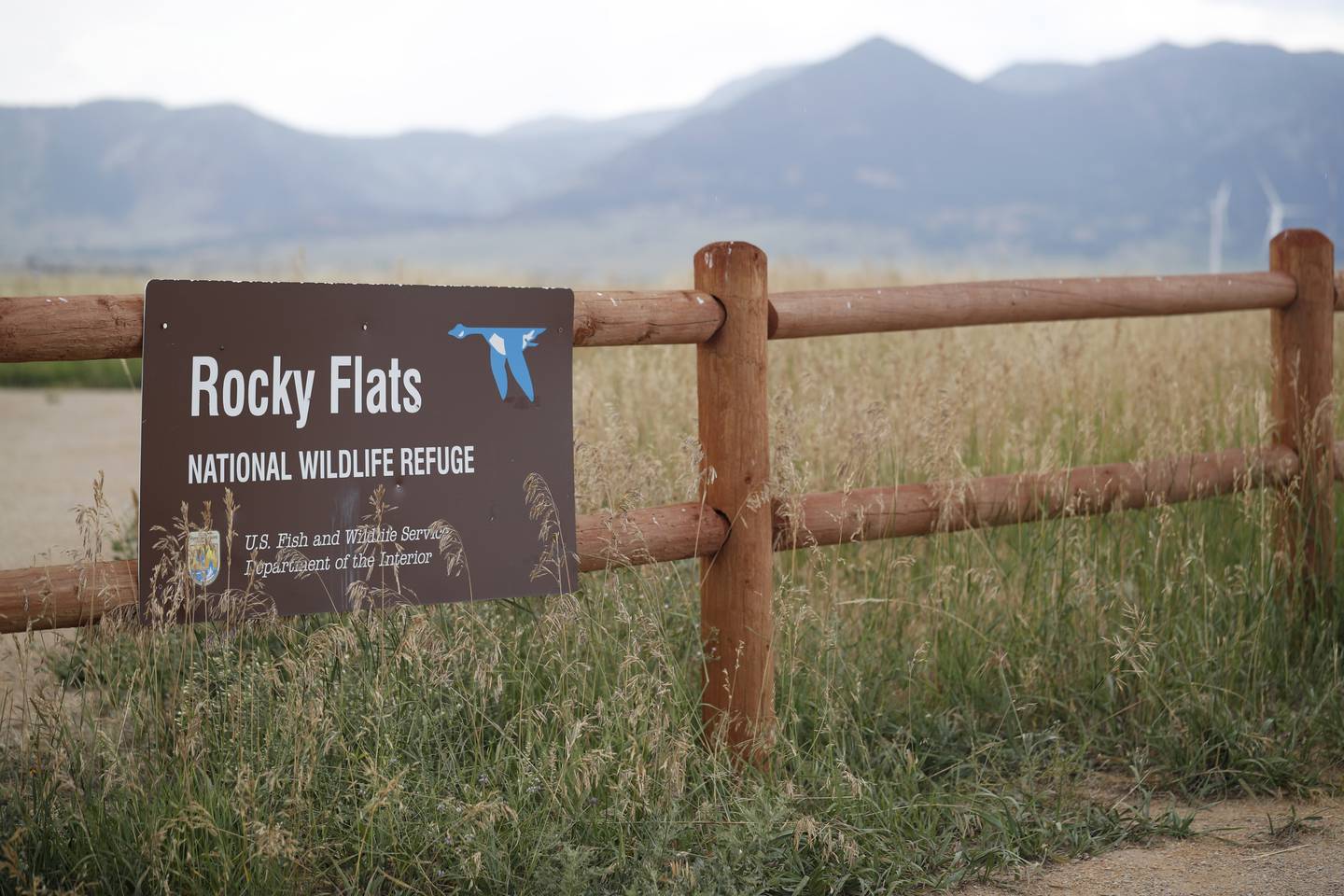 In this Aug. 7, 2019, photo, a sign hangs from a fence at the head of a trail at the Rocky Flats Wildlife Refuge in Arvada, Colo.
