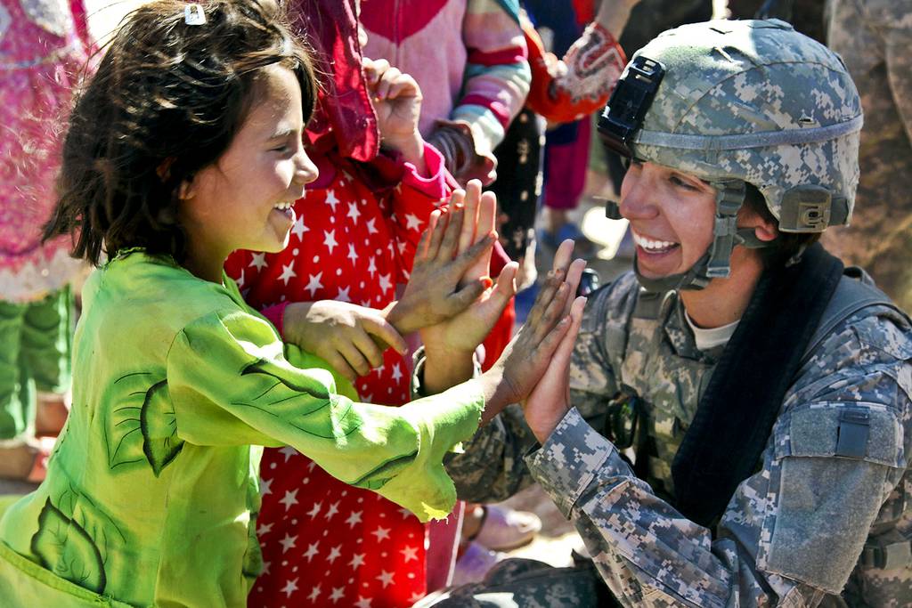 U.S. Army Sgt. Stephanie Tremmel, right, with the 86th Special Troops Battalion, 86th Infantry Brigade Combat Team, interacts with an Afghan child while visiting Durani, Afghanistan, Nov. 1, 2010.