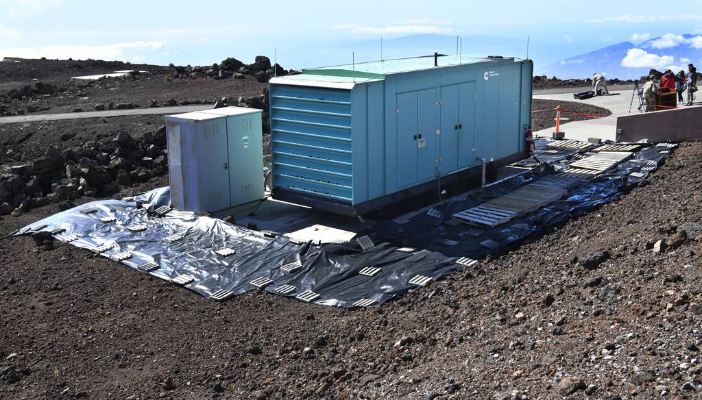 A container holding a backup generator and fuel tank sits amid black tarp covering a concrete pad and surrounding soil at Haleakala High Altitude Observatory in Hawaii on Feb. 6, 2023, where an estimated 700 gallons of diesel fuel spilled in late January.