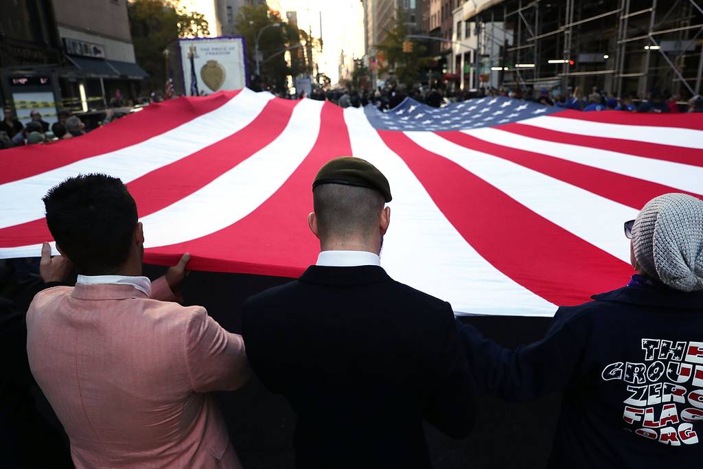 Veterans and others carry a large American flag while marching in the nation's largest Veterans Day Parade in New York City on Nov. 11, 2016.