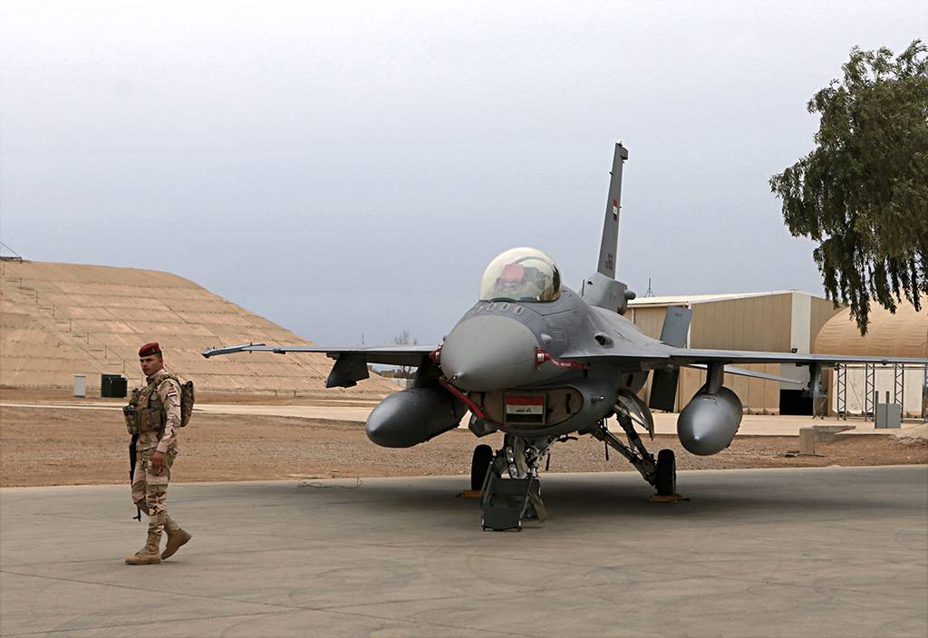 an Iraqi army soldier stand guard near a U.S.- made Iraqi Air Force F-16 fighter jet at the Balad Air Base, Iraq.