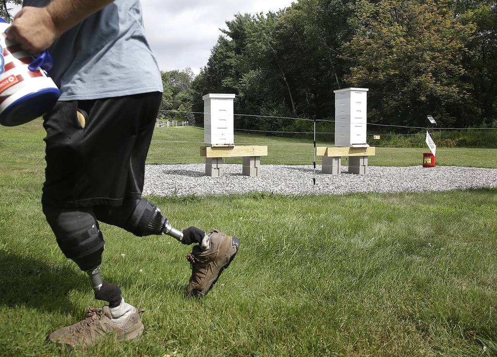 In this Aug. 7, 2019, photo, U.S. Army veteran Oscar Toce cleans up after beekeeping at the Veterans Affairs' beehives in Manchester, N.H.