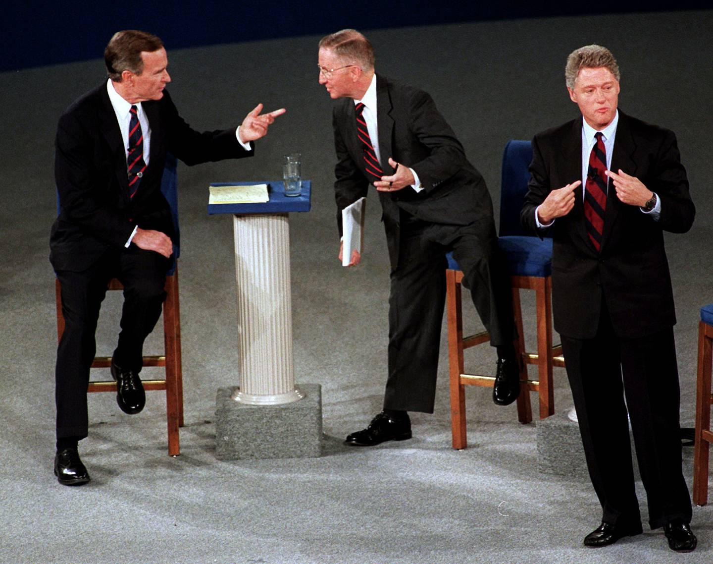 In this Oct. 15, 1992, file photo, President George H.W. Bush, left, talks with independent candidate Ross Perot as Democratic candidate Bill Clinton stands aside at the end of their second presidential debate in Richmond, Va.
