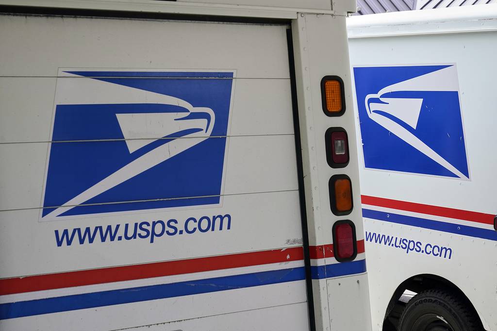 In this Aug. 18, 2020, file photo, mail delivery vehicles are parked outside a post office in Boys Town, Neb.