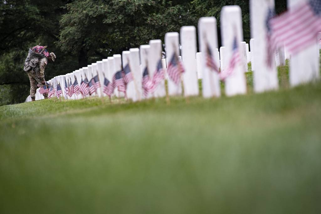 Soldiers from the 3d U.S. Infantry Regiment (The Old Guard) place U.S. flags at gravesites in Section 43 of Arlington National Cemetery, Arlington, Va., May 25, 2023.
