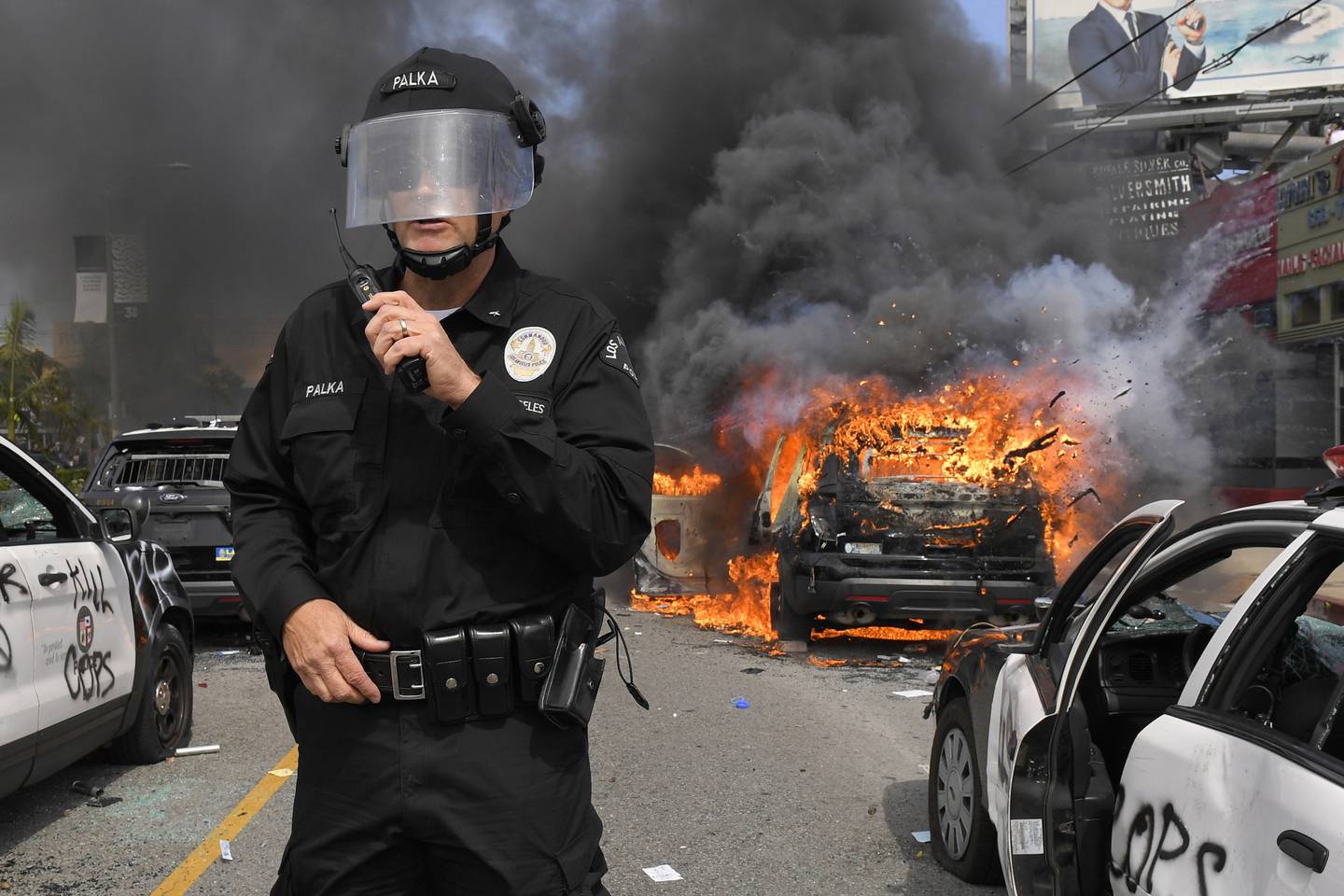 Los Angeles Police Department commander Cory Palka stands among several destroyed police cars as one explodes while on fire during a protest over the death of George Floyd, Saturday, May 30, 2020, in Los Angeles. Floyd died in police custody on Memorial Day in Minneapolis.