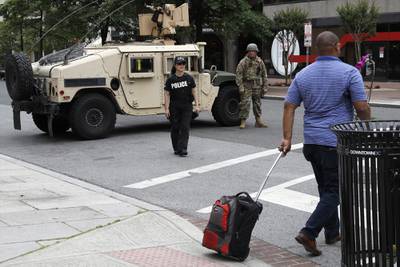 A man walks through an intersection blocked by a military Humvee from D.C. National Guard and a DEA police officer as demonstrators gather to protest the death of George Floyd, Tuesday, June 2, 2020, in Washington.