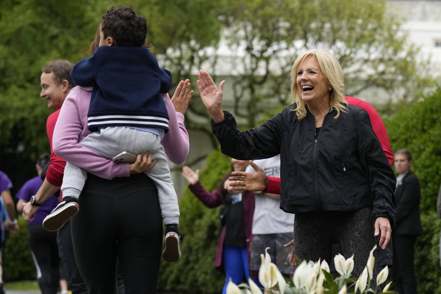 First lady Jill Biden high fives runners during the Joining Forces Military Kids Workout on the South Lawn of the White House in Washington, Saturday, April 29, 2023.