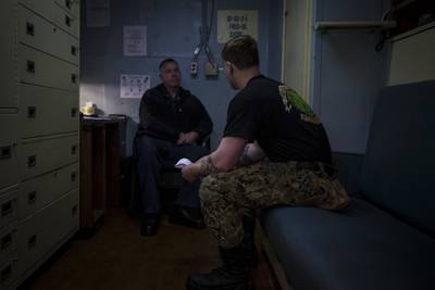 Navy Chaplain Lt. Cmdr. Ben Garrett counsels a sailor in his quarters on the USS Bataan on Monday, March 20, 2023 at Norfolk Naval Station in Norfolk, Va.