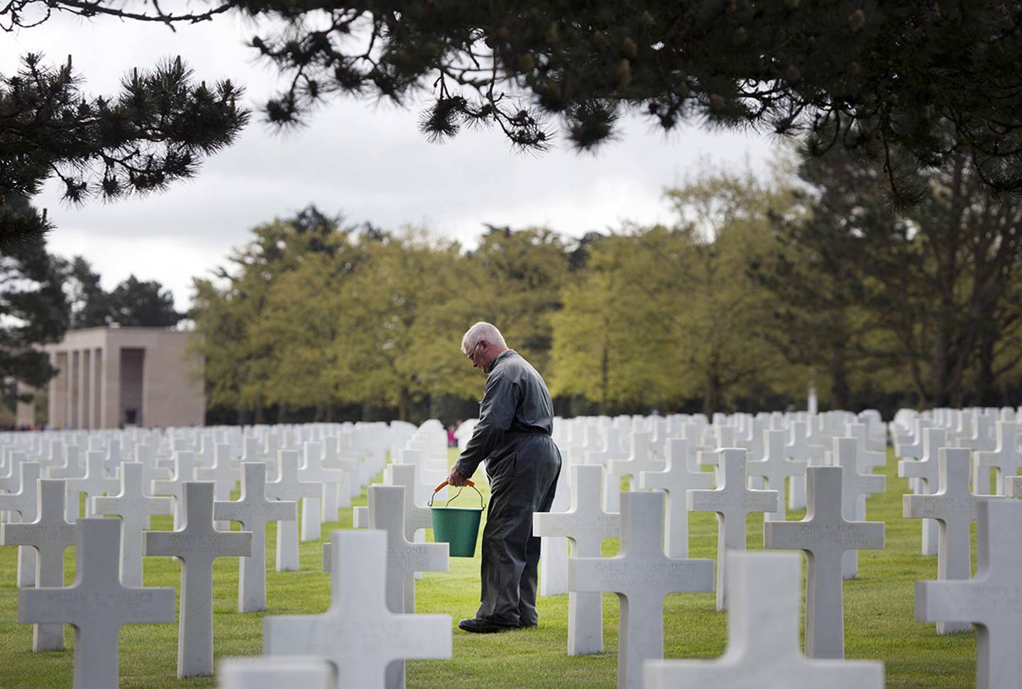 Normandy American Cemetery worker cleans headstones.