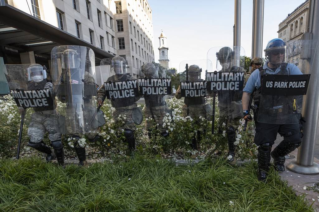 In this June 1, 2020, file photo, District of Columbia National Guard, and U.S. Park Police, advance through the white roses in front of the AFL-CIO headquarters, with St. John's Church behind them, as they move demonstrators back after they gathered to protest the death of George Floyd near the White House in Washington.