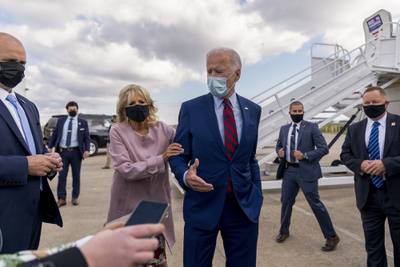 Jill Biden moves her husband, Democratic presidential candidate former Vice President Joe Biden, back from members of the media as he speaks outside his campaign plane in New Castle, Del., on Oct. 5, 2020.