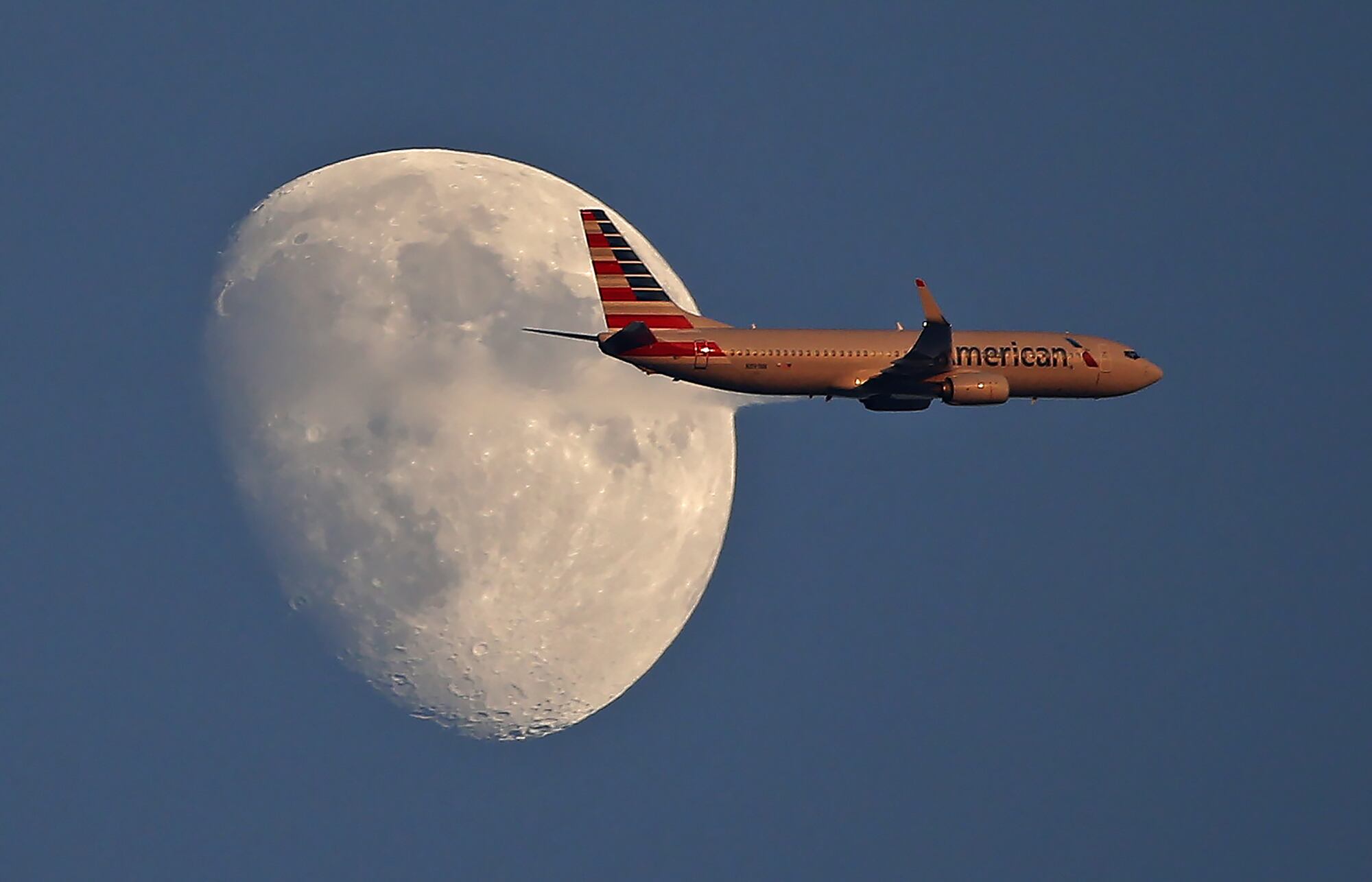 An American Airlines jetliner flies past the moon on Sept. 1, 2017, in Arlington, Texas.
