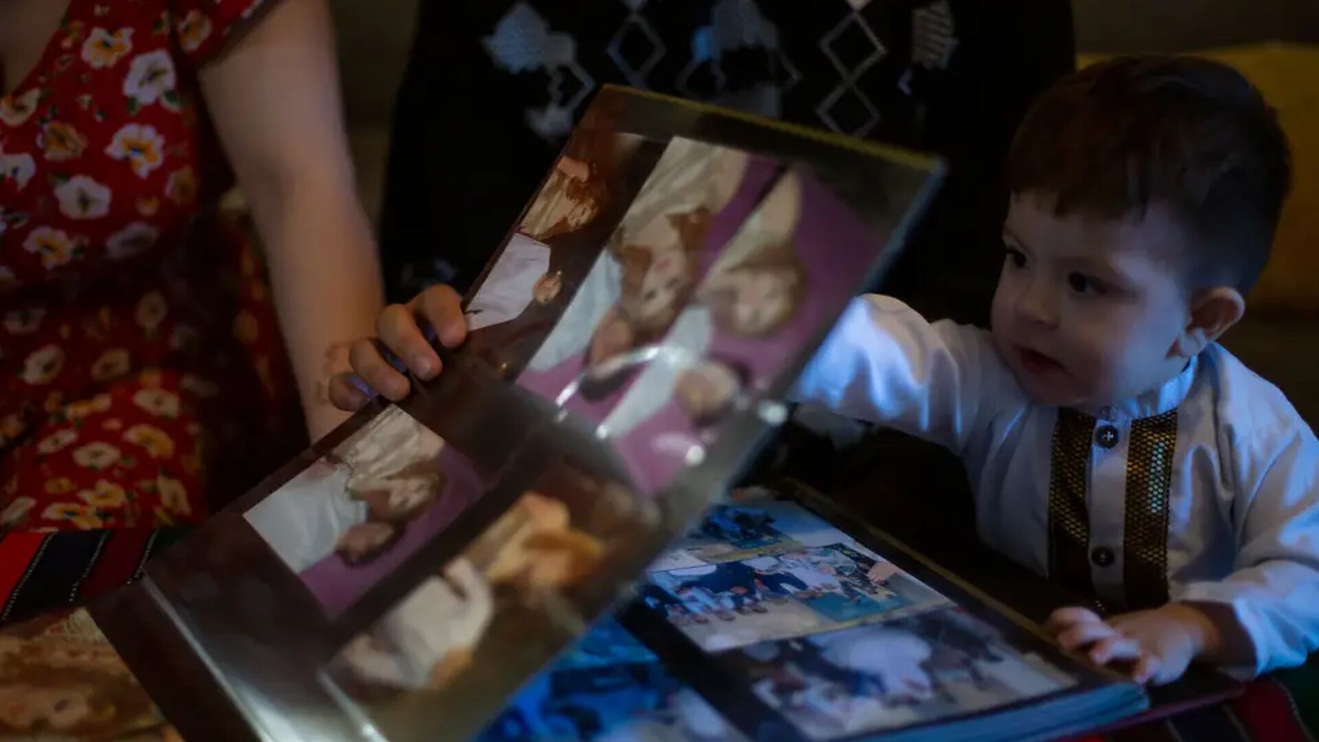 At their home in Austin, Azita Jawady, her husband Hamid Sadra and their 1-year-old son Qmars look through wedding photos from Afghanistan.