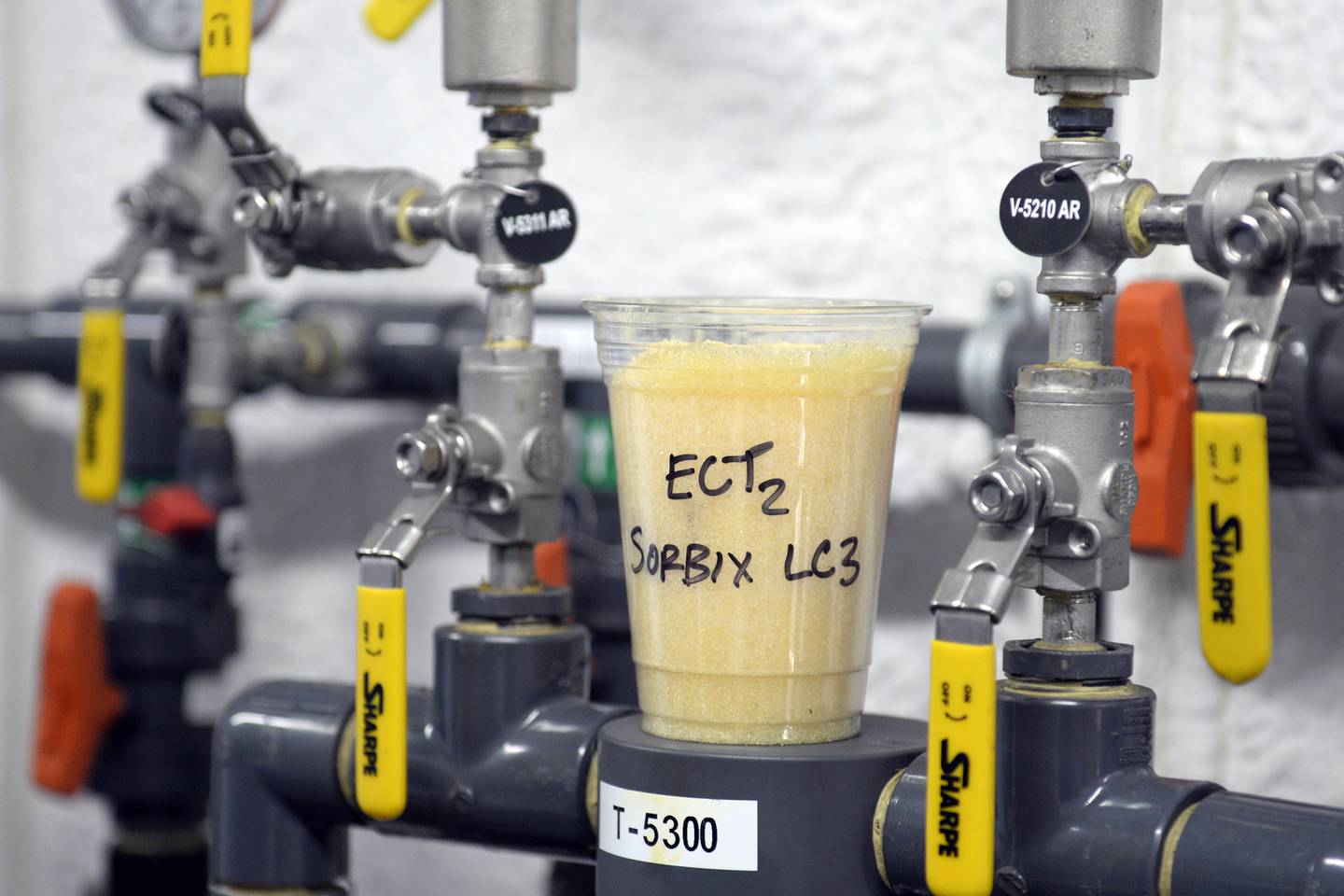 A cup full of single-use, ion-exchange, gel-based media sits atop valves that control a ground water remediation system being used to remediate polyfluoroalkyl substances (PFAS) from groundwater at the fire training area of Wright-Patterson Air Force Base, Ohio on Sept. 29, 2020.