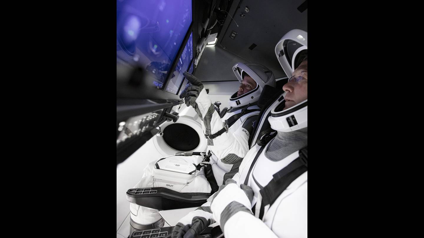In this March 19, 2020, photo, astronauts Doug Hurley, foreground, and Bob Behnken work in SpaceX's flight simulator at the Kennedy Space Center in Cape Canaveral, Fla.