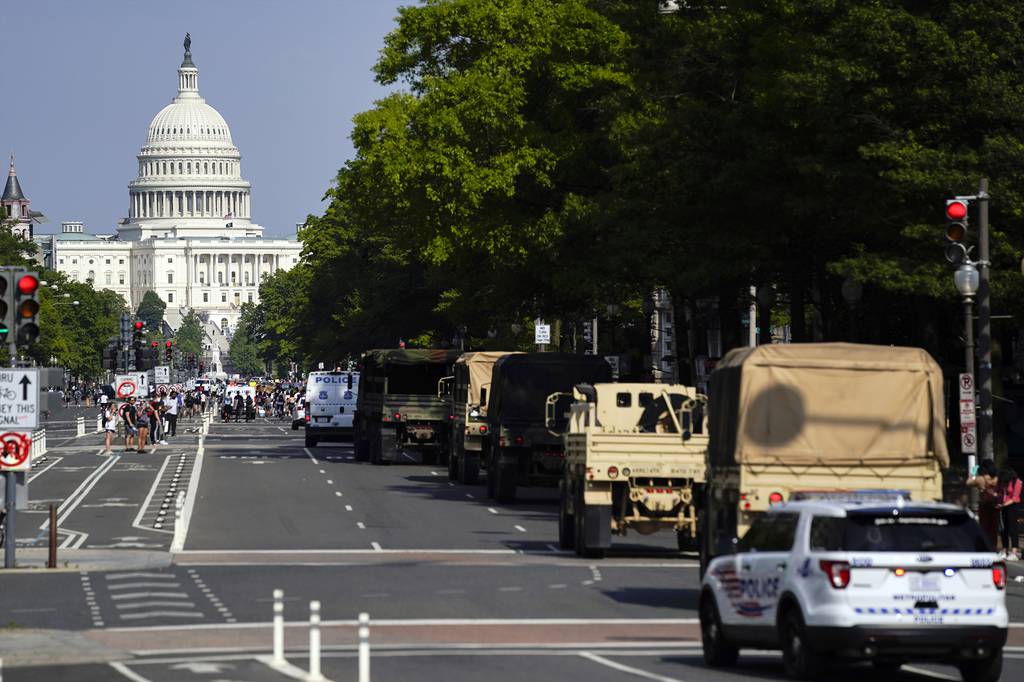 Demonstrators walk along Pennsylvania Avenue as a line of police and military vehicles drive as they protest the death of George Floyd, Wednesday, June 3, 2020, in Washington.
