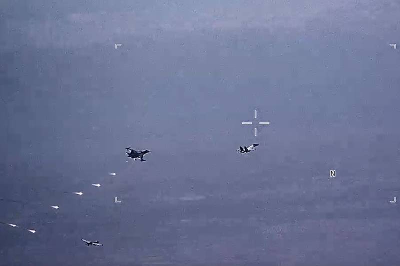 In this image from video released by the U.S. Air Force, Russian military SU-34 and SU-35 aircraft release flares in the flight path of a U.S. Air Force MQ-9 Reaper drone, lower left, on Thursday, July 6, 2023, over Syria.