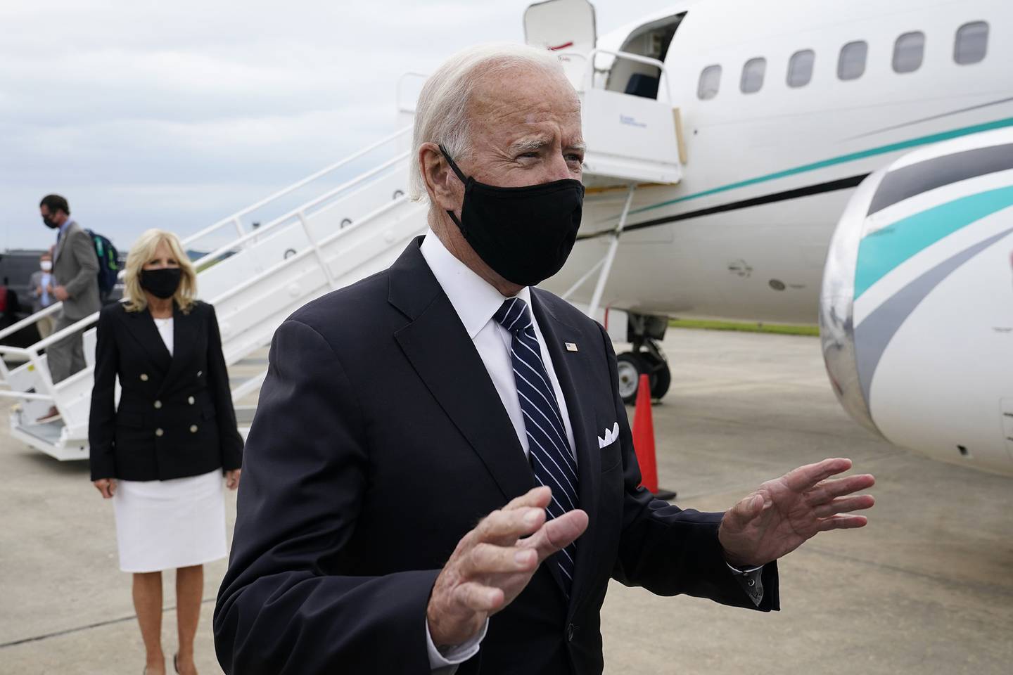 Democratic presidential candidate and former Vice President Joe Biden speaks with reporters after he and his wife Jill Biden, back left, stepped off a plane at New Castle Airport in New Castle, Del., Friday, Sept. 11, 2020.